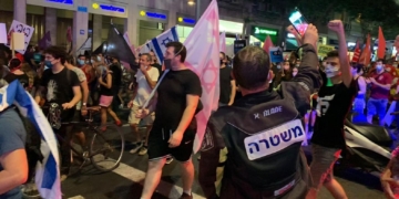 שוטר מצלם מפגינים בצעדה בתל אביב לפני כשבועיים