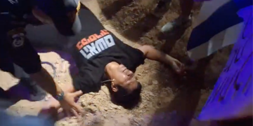 הלן פרידמן שוכבת בהכרה מעורפלת אמש בקיסריה | צילום מסך מתוך סרטון תיעוד ההפגנה. שימוש ע״פ סעיף 27 א׳