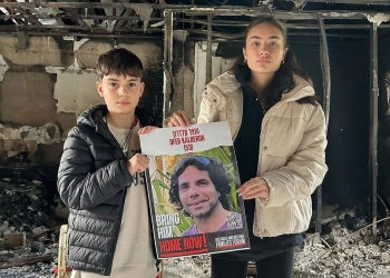 סהר (17) וארז (12) ששוחררו משבי חמאס בנובמבר ותמונת אביהם, עופר קלדרון, שעדיין בעזה
