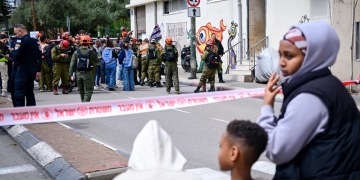 מבקשי מקלט על רקע זירת פגיעה של פצצת מצרר מאיראן בדרום תל אביב הבוקר | צילום: אבשלום ששוני, פלאש 90