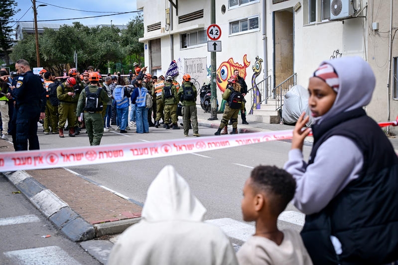 מבקשי מקלט על רקע זירת פגיעה של פצצת מצרר מאיראן בדרום תל אביב הבוקר | צילום: אבשלום ששוני, פלאש 90
