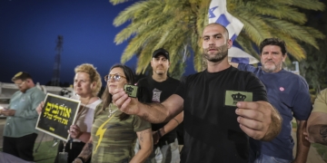 אנשים עם דגלי ישראל וסמלי ״משיח״ מפגינים כנגד מאסר של חייל על לבישת פאץ׳ משיח