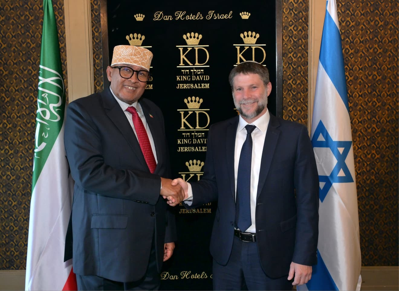 שר האוצר של מדינת ישראל, בצלאל סמוטריץ׳, לוחץ את ידו של נשיא סומלילנד עבד א-רחמאן מוחמד עבדאללה. לידם דגלים של ישראל וסומלילנד