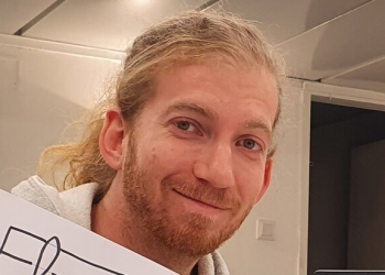 גבר בלונדיני מחייך למצלמה. טל רוזנבליט