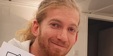 גבר בלונדיני מחייך למצלמה. טל רוזנבליט